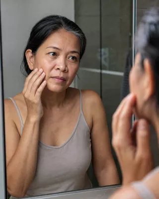 Woman checking her skin in the mirror