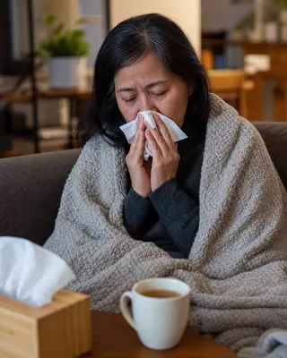 Woman wrapped in a blanket with a cold